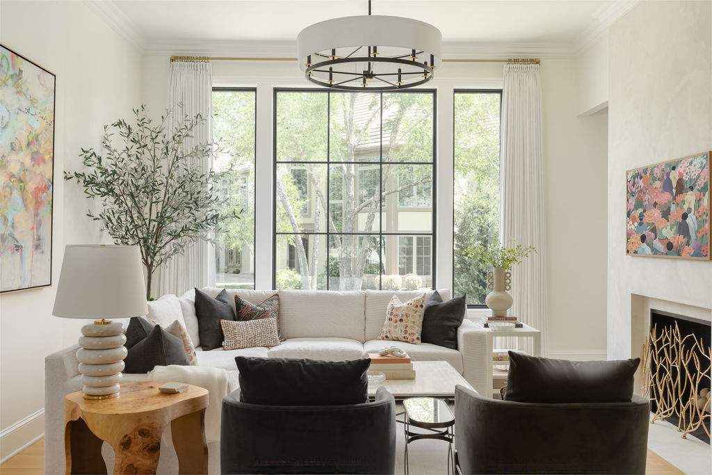 Living room with large black-framed grid windows, fireplace, and neutral furniture in a Leawood, KS home