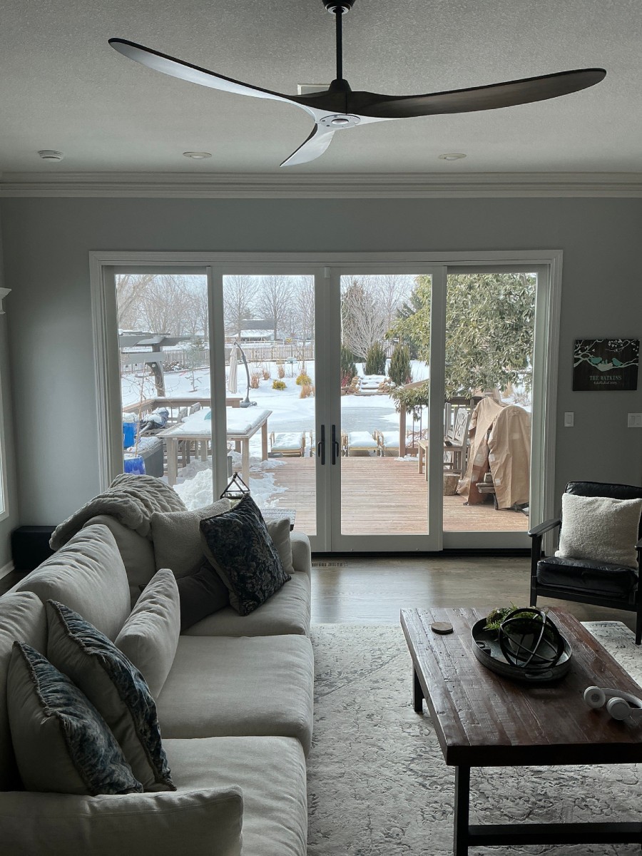 Living room with new white-framed French patio doors overlooking a snowy backyard deck, interior view in a Liberty, MO home
