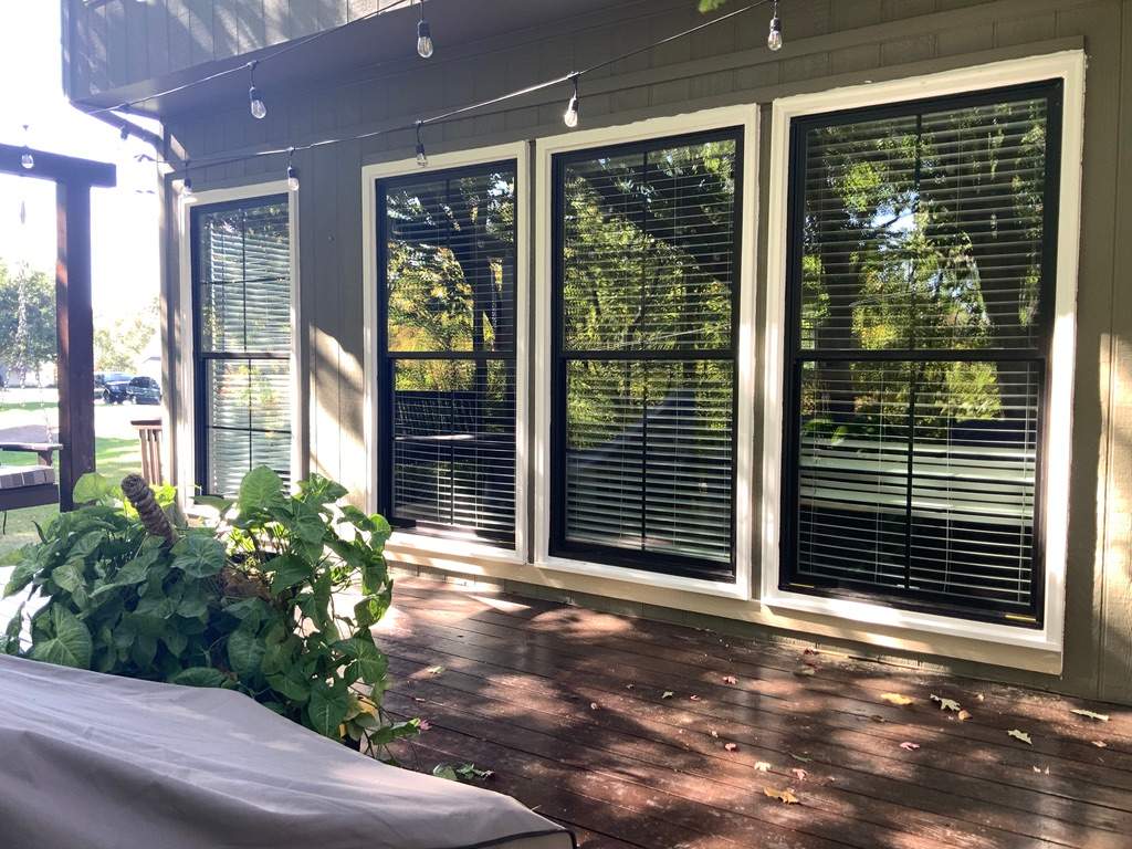 Row of new black-framed windows with white trim on a deck-side wall surrounded by trees in Parkville, MO