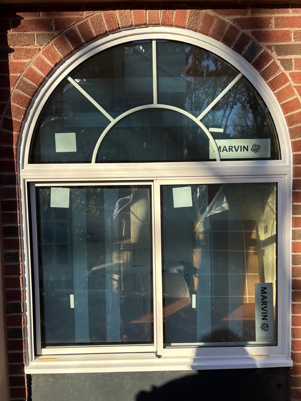 Newly installed Marvin arched-top window with divided-light transom on a brick home in Kansas City, MO