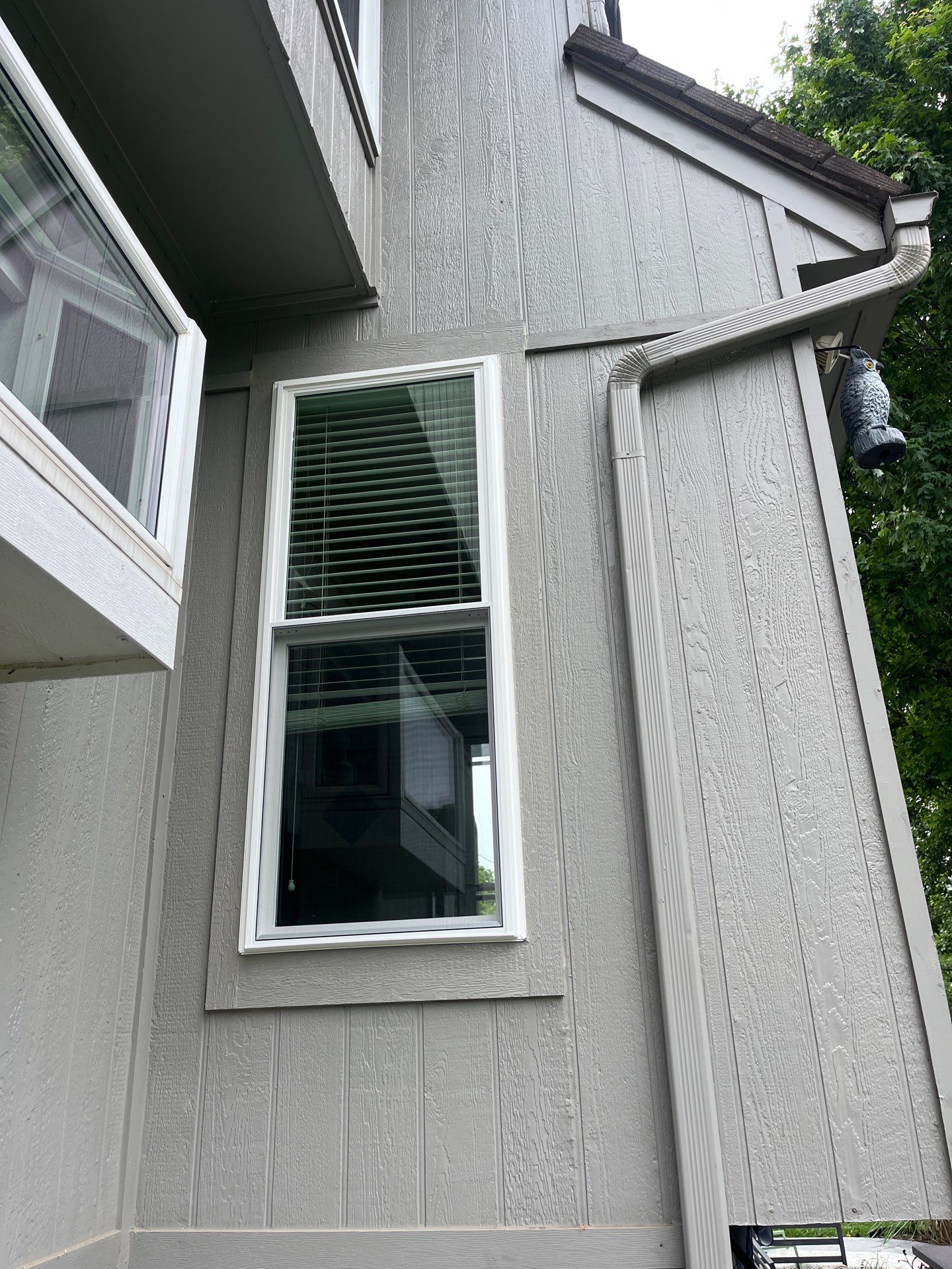 New white double-hung window on gray board-and-batten siding, exterior view in Olathe, KS
