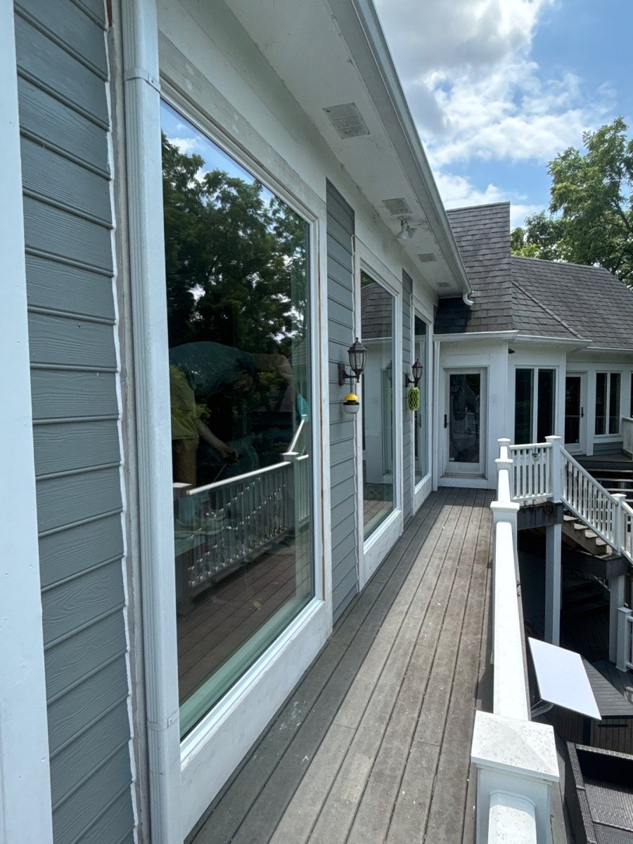 White-trimmed home exterior with large multi-pane windows and an exterior staircase beside a gray shingled roof