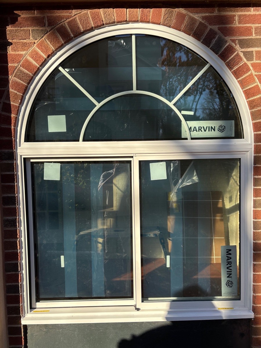 Marvin arched window with divided-lite grid above a double-hung window, set in a brick opening